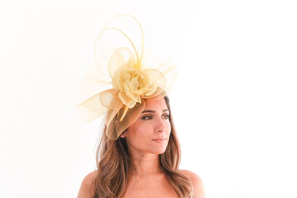 Golden Yellow tones Crinoline Fascinator perced on the front left on looking of the models head as she stares off to the right.