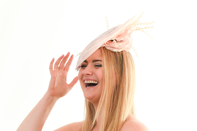 Light Pink Hatinator with underside silk flower visiabe on the laughing model as she raises her hand.